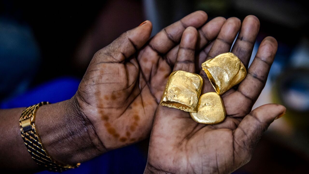 Tanzanian miner Assia Hussein, who is the chairman of an only-women miners association, observes some pure gold nuggets at a gold market in Geita, Tanzania on May 28, 2022. - Tanzania is a land rich in minerals and one of the main gold producers in Africa, with gold representing more than 90% of the country's mineral exports. Artisanal and small-scale gold mining have culturally and historically relegated women's participation. The extractive sector in Tanzania has historically been a male-dominated industry with high levels of harassment, sexual abuse, discrimination and misconceptions over women's involvement, and contributions following traditional beliefs. A a result women face economic challenges due to lack of access to the land. Through the creation only-women miners associations and the help of projects advocating for rights and inclusion in the extractive industry such as the Collective Action For Rights Realisation In Extractives Industry (CLARITY), Tanzanian women in Geita region have been gradually gaining access to the mines while being able to benefit from the sector. (Photo by LUIS TATO / AFP) (Photo by LUIS TATO/AFP via Getty Images)